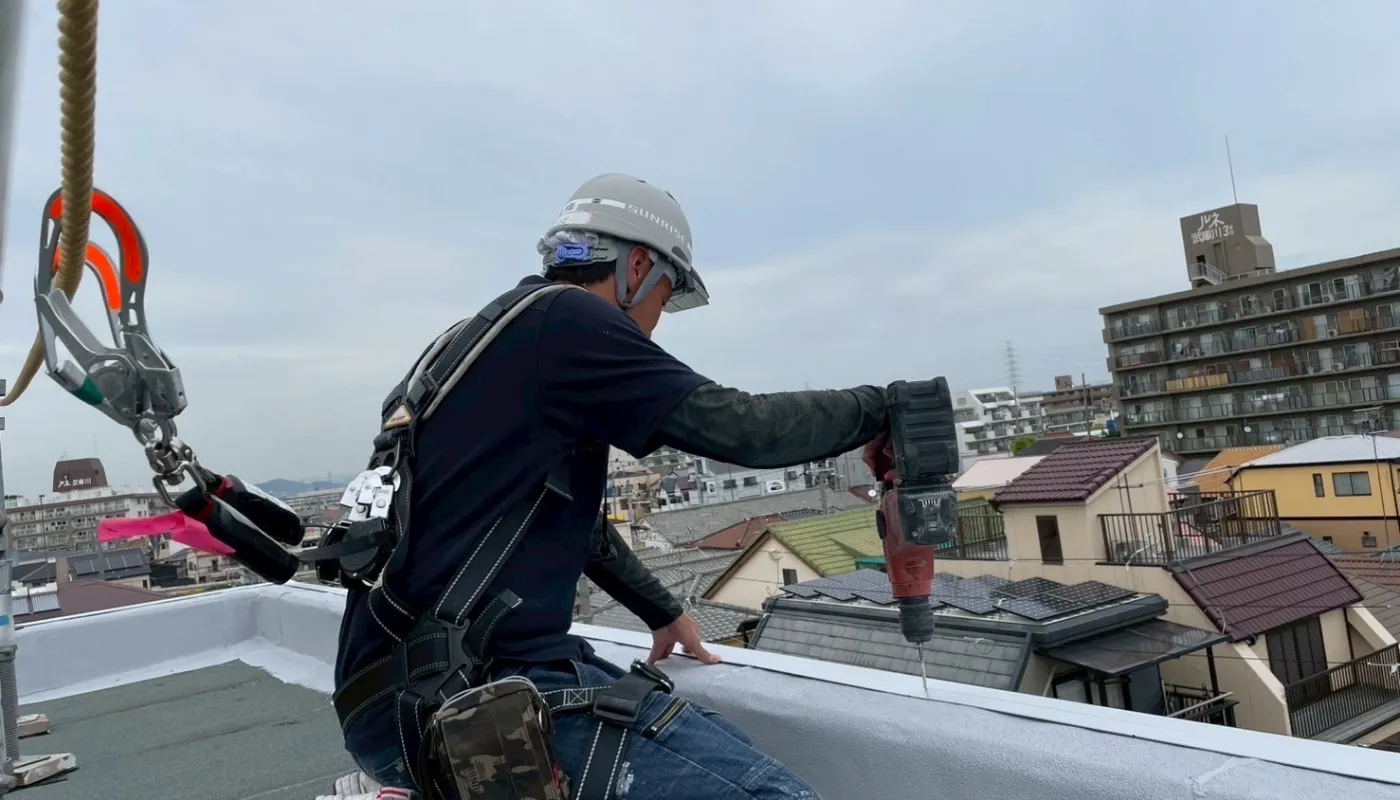 作業員が屋根の防水工事をしているところ